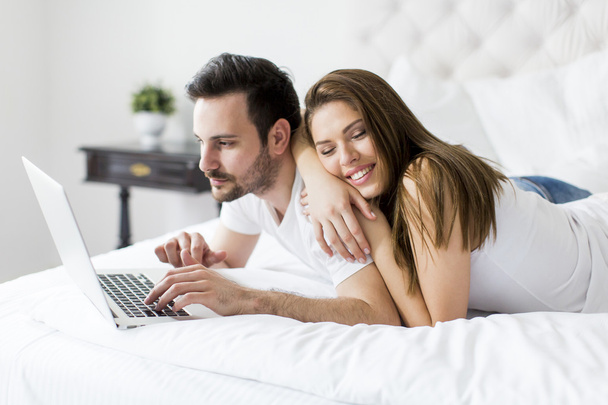 Couple with laptop in the bed - 写真・画像