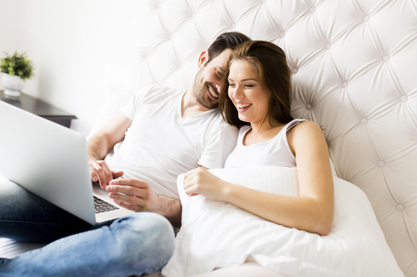 Couple avec ordinateur portable dans le lit
 - Photo, image