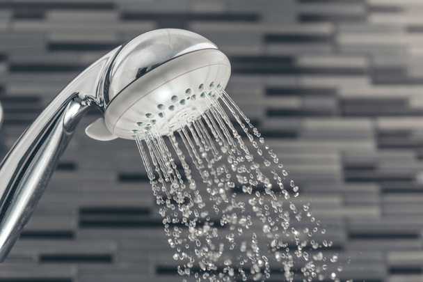 Cabeça de chuveiro com gotas de água caindo em um banheiro
 - Foto, Imagem