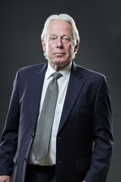 Hombre de negocios senior con traje azul oscuro y corbata aislada sobre fondo oscuro
. - Foto, imagen