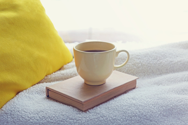 Cup of tea, book and warm blanket on windowsill, close up - 写真・画像