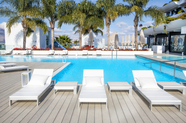 Swimming pool area with  white sun beds at the modern resort. - Photo, Image