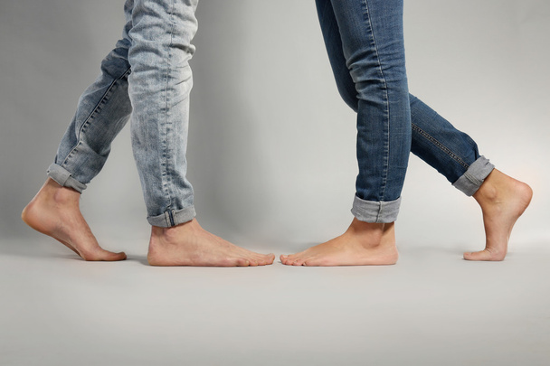 Young couple in blue jeans standing on grey background - Valokuva, kuva