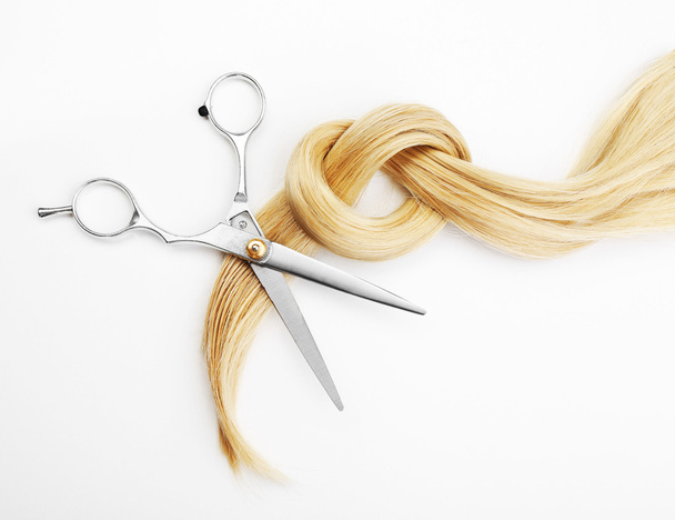 Hairdresser's scissors with strand of blonde hair, isolated on white - Foto, imagen