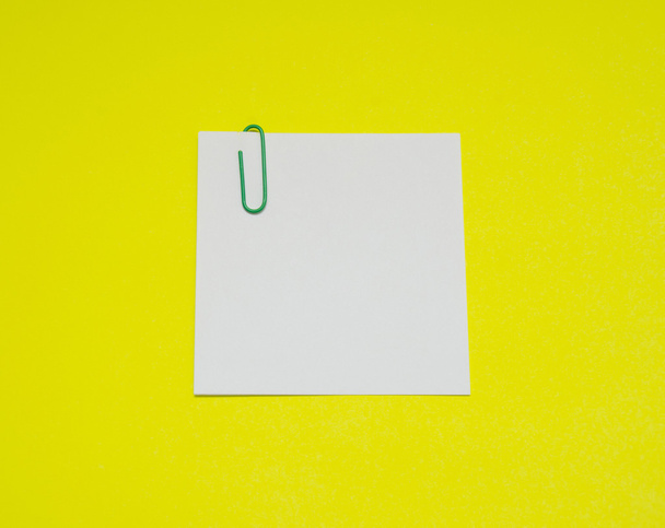 note with color paper clip isolated on yellow background - Photo, Image