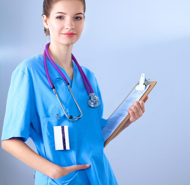 Smiling female doctor with a folder in uniform standing at hospital - Fotoğraf, Görsel