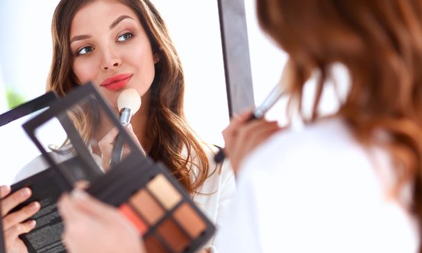 Young beautiful woman making make-up near mirror - Foto, imagen