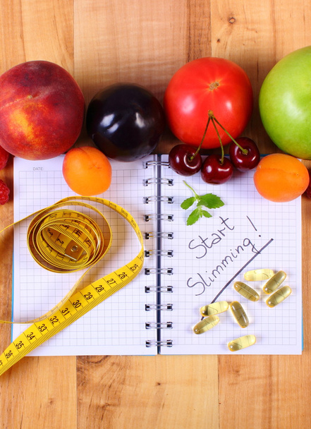 Hedelmät, tabletit lisäravinteet ja senttimetri kannettavalla, laihtumiseen ja terveelliseen ruokaan
 - Valokuva, kuva