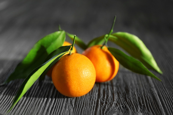 Fresh tangerines with leaves on wooden table, closeup - Fotó, kép
