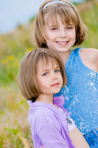 Joyeuses petites sœurs sur fond de prairie verte
 - Photo, image