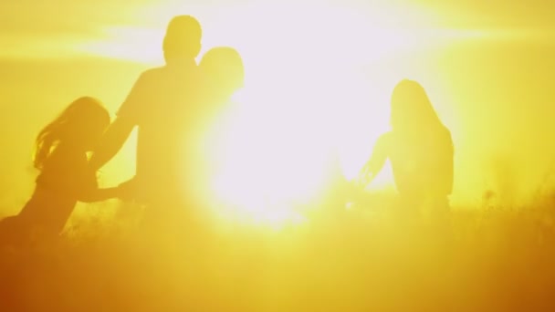 rodziców z córkami na łące na zachodzie słońca - Materiał filmowy, wideo