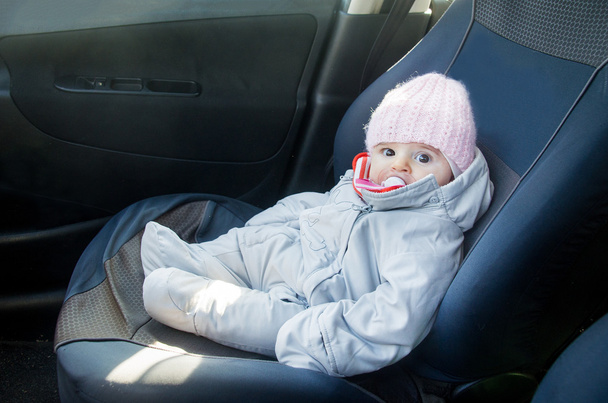 noworodka w samochodzie siedzi na przednim siedzeniu ubrany na zimę - Zdjęcie, obraz
