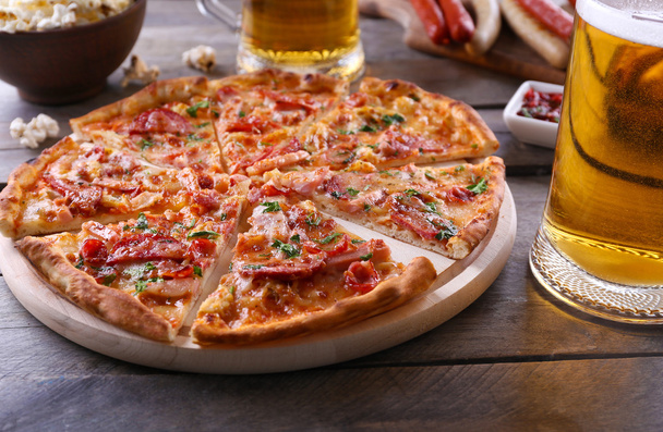 Sliced pizza and glass of beer on wooden table, close up - Foto, Imagen