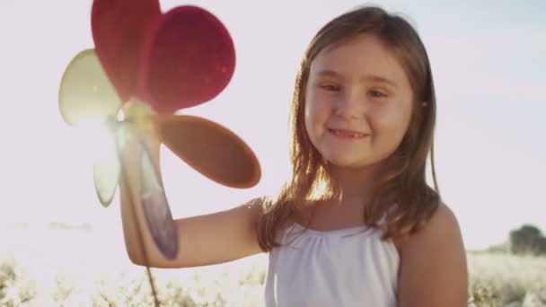 malá holčička v louce hraje s hračkou větrný mlýn - Záběry, video