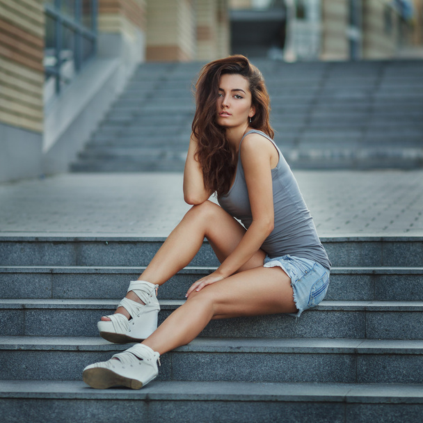 Stile di vita all'aperto ritratto di bella ragazza in posa sulle scale, indossando in stile urbano hipster su sfondo urbano
. - Foto, immagini
