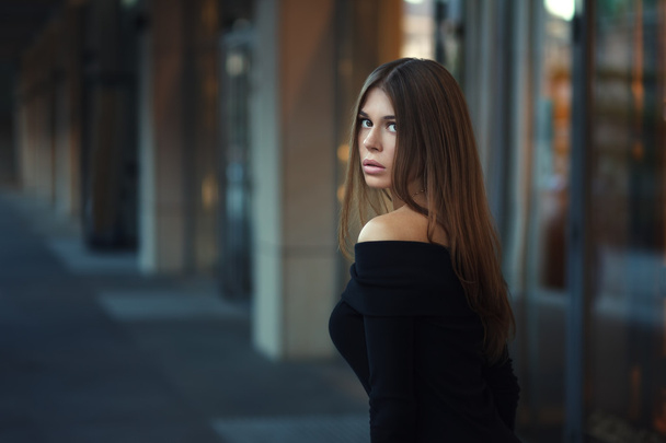 Gyönyörű barna fiatal nő, szép fekete ruhában. A városi háttér pózol. Divatfotó - Fotó, kép