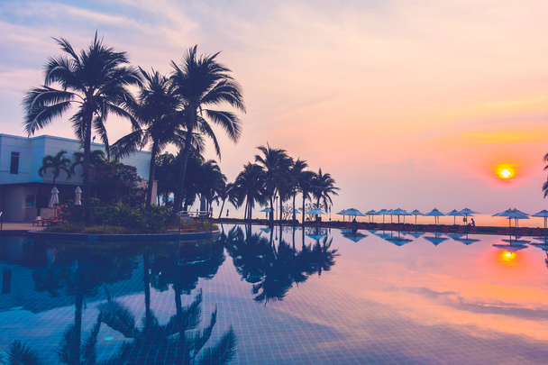 Silhouetten van palmbomen op zwembad - Foto, afbeelding