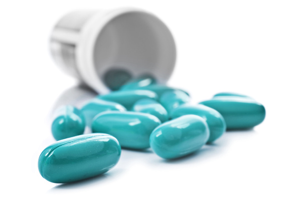 blaue Pillen und Tablettenflasche auf weißem Hintergrund - Foto, Bild