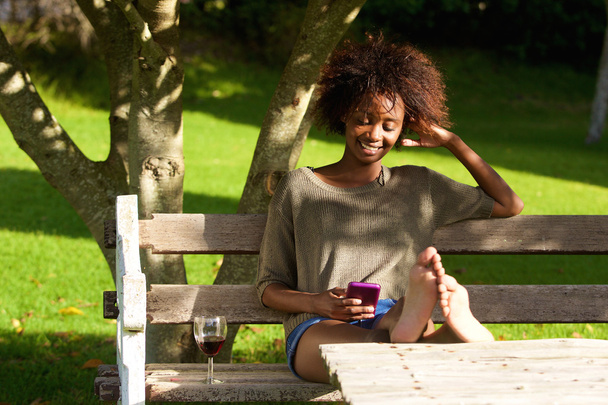 Sonriente mujer negra sentada en el parque
 - Foto, imagen