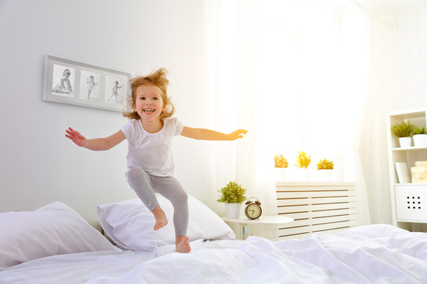 gelukkig kind meisje springt en speelt bed - Foto, afbeelding