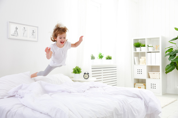 happy child girl jumps and plays bed - Φωτογραφία, εικόνα