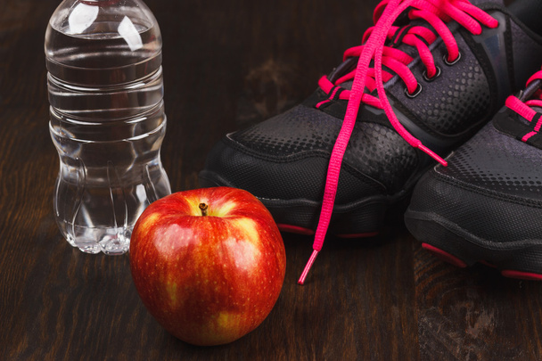 Zapatillas, manzana y botella de agua, fondo de madera
 - Foto, Imagen