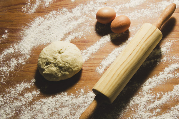 Œufs, rouleau à pâtisserie et pâte sur la table en bois dans la cuisine
.  - Photo, image