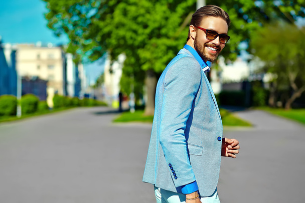 High fashion look.Young stylish confident happy handsome  businessman model man in blue suit cloth lifestyle in the street behind sky in sunglasses - Fotó, kép