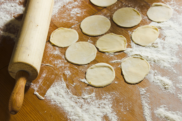 Cercles faits maison de pâte et rouleau à pâtisserie sur la table en bois
. - Photo, image