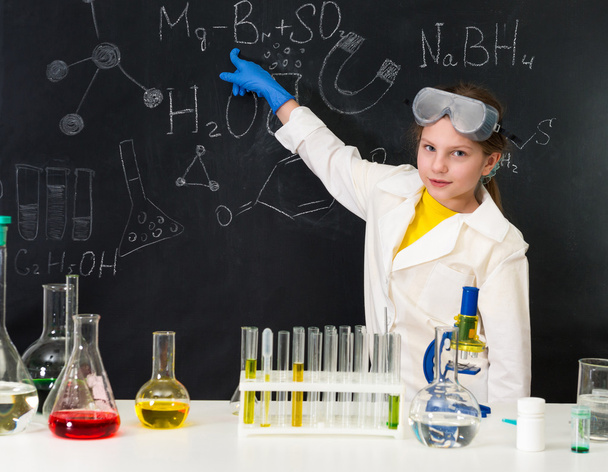 schoolgirl in chemistry lab pointing at formula on blackboard - Фото, зображення