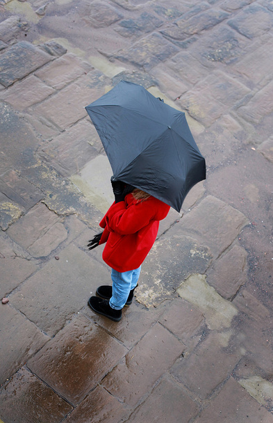 Κοιτάζοντας προς τα κάτω σε μια γυναίκα με μια ομπρέλα σε μια υγρή ημέρα - Φωτογραφία, εικόνα