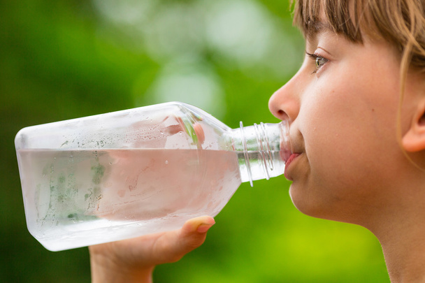 Meisje schoon kraanwater drinken uit transparante glazen fles - Foto, afbeelding