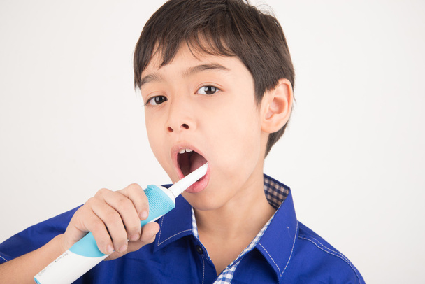 Μικρό αγόρι χρησιμοποιώντας ηλεκτρικές οδοντόβουρτσες σε άσπρο φόντο - Φωτογραφία, εικόνα