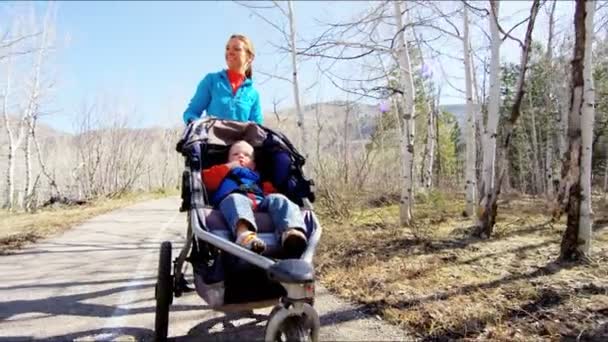 Mutter mit Sohn im Kinderwagen genießt Spaziergang im Park - Filmmaterial, Video