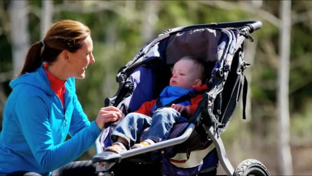 Mutter mit Sohn im Kinderwagen genießt Spaziergang im Park - Filmmaterial, Video