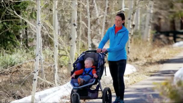 madre con hijo en cochecito disfrutando caminar en parque
 - Metraje, vídeo