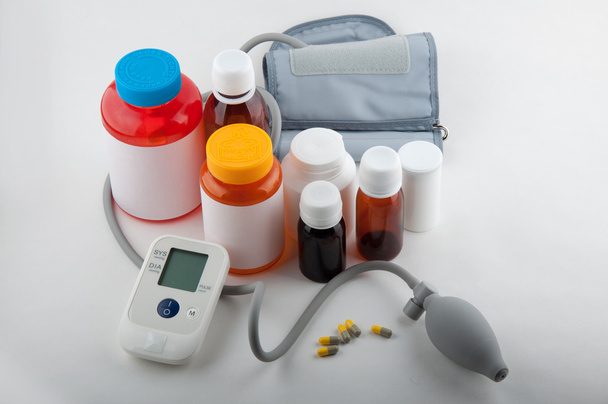 Blutdruckmessgerät und Fläschchen für Tabletten auf weiß - Foto, Bild