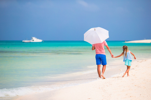 otec a dcera na pláži s deštníkem schovat před sluncem - Fotografie, Obrázek