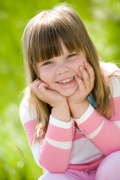 Little girl wearing pink blouse on green summer grass - Fotografie, Obrázek