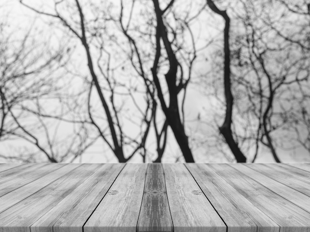 Drewniana tablica pusta tabela przed tło zamazane pole. Perspektywa szary drewna ponad rozmycie drzew w lesie - mogą być używane do wyświetlania lub montaż produktów. sezon wiosna. sztuka obrazu filtrowanego. - Zdjęcie, obraz