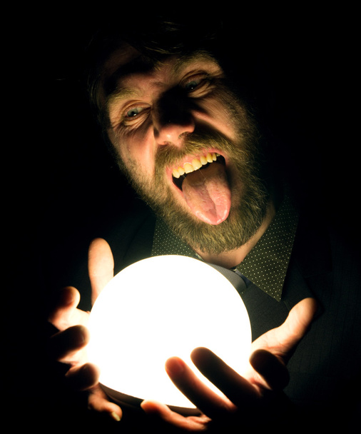 bearded man in the dark, holding in front of a lamp, expresses different emotions - Foto, afbeelding