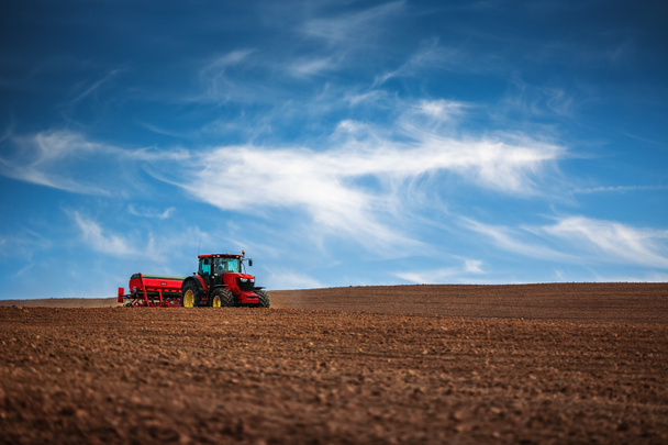 Farmer with tractor seeding crops at field - Foto, Bild