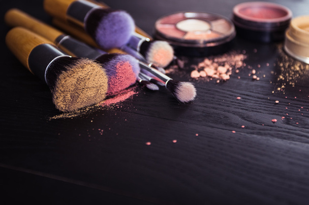 make up brushes with powder and rouge on a black wooden background - Photo, Image