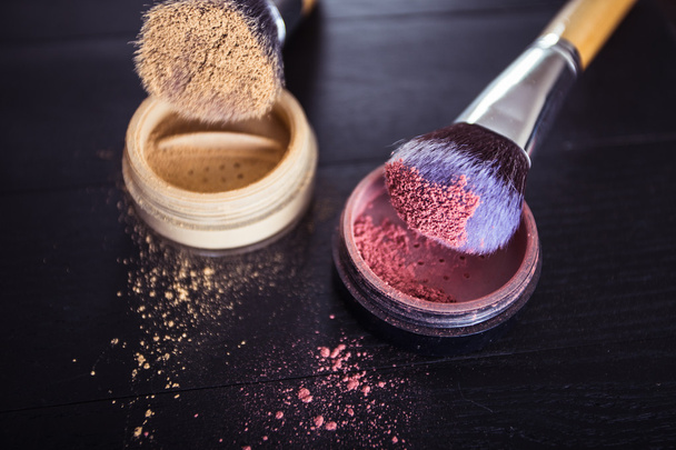 Make-up Pinsel mit Puder und Rouge auf schwarzem Holzgrund - Foto, Bild