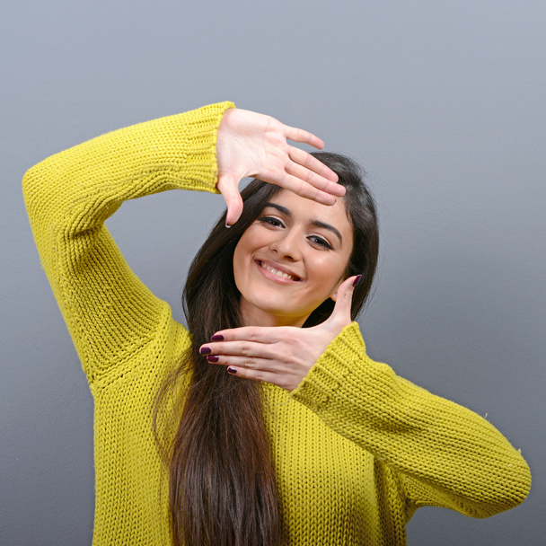 Portret van een jonge vrouw maken frame met handen tegen grijs b - Foto, afbeelding