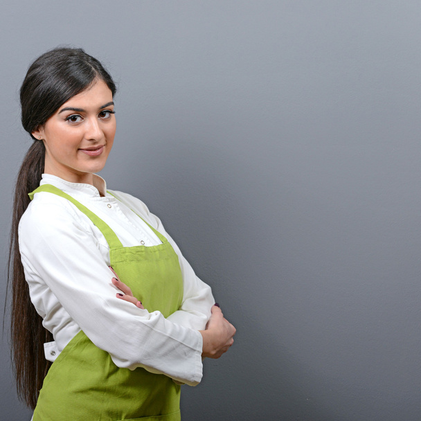 Portrait of confident beautiful woman chef against gray backgrou - Foto, Bild