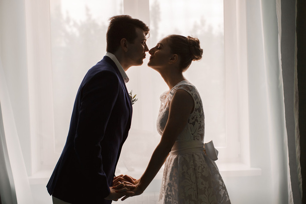 Newlyweds kissing at the window, silet - Valokuva, kuva