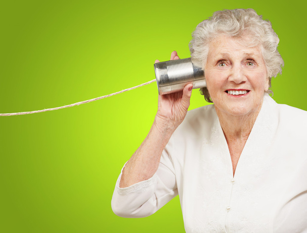 Portrait de femme âgée entendant avec boîte de conserve en métal sur vert b
 - Photo, image