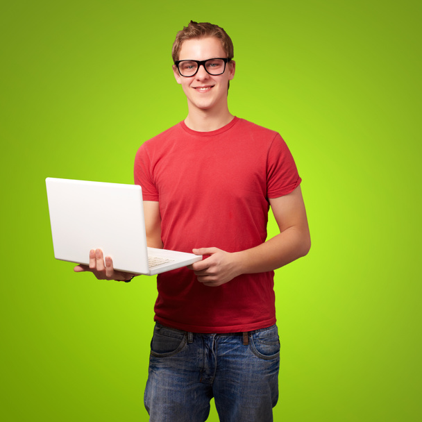 Retrato de un joven estudiante sosteniendo portátil sobre fondo verde
 - Foto, Imagen