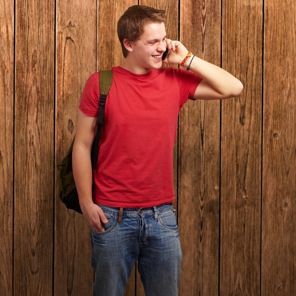 Mobil ahşap bir duvara konuşan genç adam portresi - Fotoğraf, Görsel